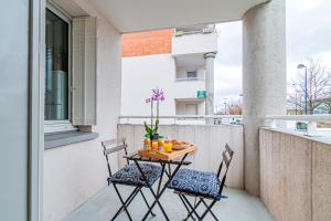 a table and two chairs on a balcony with oranges at Appart moderne tout confort La Clef d'Élancourt in Élancourt