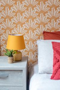 a bedroom with a bed with a lamp on a night stand at Appart moderne tout confort La Clef d'Élancourt in Élancourt