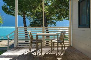 een tafel en stoelen op een veranda met uitzicht op de oceaan bij Campeggio Garda in Limone sul Garda