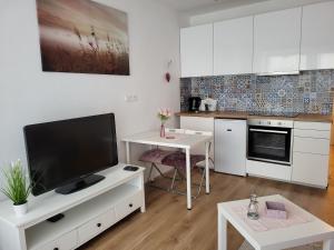 a kitchen with white cabinets and a flat screen tv at Príjemný apartmán s parkovaním in Nivy