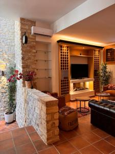 APARTAMENTOS VILLA DE GOYA في Fuendetodos: غرفة معيشة مع جدار حجري وتلفزيون