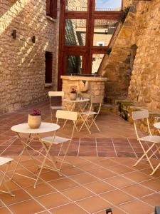 un patio con sillas, mesas y una pared de ladrillo en APARTAMENTOS VILLA DE GOYA, en Fuendetodos