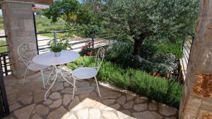 a table and chairs on a patio with a tree at Holiday house Valencan 2 in Mednjan