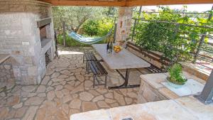 an outdoor patio with a table and a hammock at Holiday house Valencan 2 in Mednjan