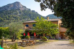 a building with a picnic table with a mountain in the background at LA FONTAINE D'ANNIBAL in Buis-les-Baronnies