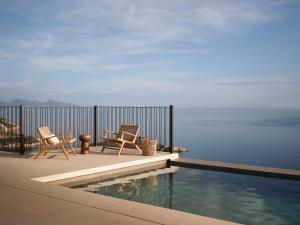 two chairs and a swimming pool on a balcony with the ocean at Verdante Villas , Quintessential SeaView Living, By ThinkVilla in Agios Nikolaos