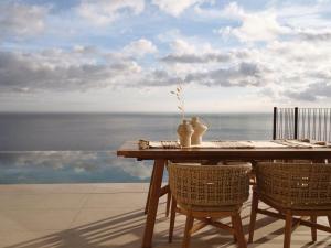 a wooden table with two chairs and a view of the ocean at Verdante Villas , Quintessential SeaView Living, By ThinkVilla in Agios Nikolaos
