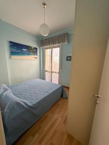 een slaapkamer met een blauw bed en een raam bij Appartamento a 2 passi dal mare in Alba Adriatica