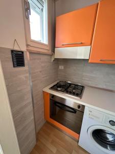 een kleine keuken met oranje kasten en een fornuis bij Appartamento a 2 passi dal mare in Alba Adriatica