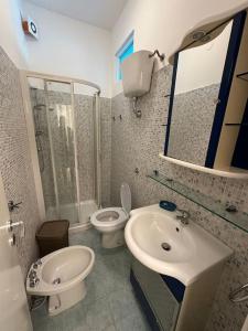 een badkamer met een wastafel, een toilet en een spiegel bij Appartamento a 2 passi dal mare in Alba Adriatica