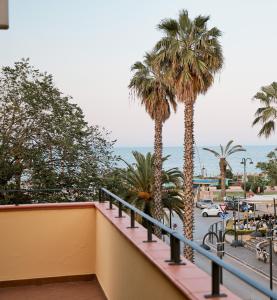 einen Balkon mit Palmen und Meerblick in der Unterkunft Discover Tortoreto in Tortoreto Lido