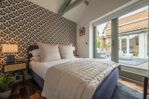 a bedroom with a bed and a large window at Tern Cottage in Burnham Market