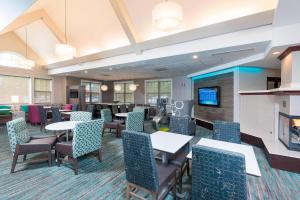 uma sala de jantar com mesas e cadeiras e uma televisão em Residence Inn by Marriott Grand Rapids West em Grand Rapids