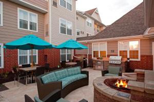 d'une terrasse avec deux parasols bleus et un foyer extérieur. dans l'établissement Residence Inn by Marriott Grand Rapids West, à Grand Rapids