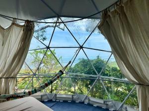 una cúpula de cristal con hamaca en una habitación en Tropical eGlamping, en Tân Phú