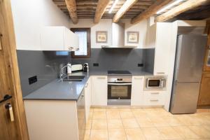 a kitchen with white cabinets and black counter tops at Mas el Coll in El Gurb