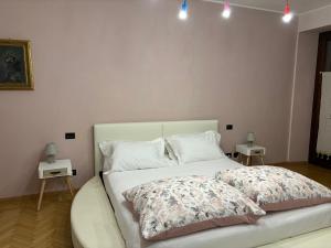 1 dormitorio con 1 cama blanca y 2 mesitas de noche en Casa in centro Domodossola self check in, en Domodossola