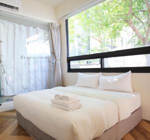 una camera da letto con un letto con due asciugamani sopra di Yes Yes I Am Willing a Tainan