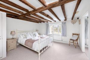 a white bedroom with a bed and a chair at The Milkhouse Cottage by Huluki Sussex Stays in Ashurst