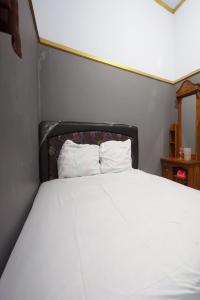 uma cama com duas almofadas brancas num quarto em SPOT ON 93620 Anisa Homestay Syariah em Tulungagung