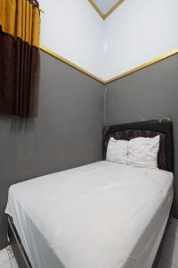 uma cama com lençóis brancos e almofadas num quarto em SPOT ON 93620 Anisa Homestay Syariah em Tulungagung