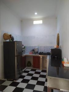 een keuken met een zwarte koelkast en een geruite vloer bij Homestay Propline in Bogor