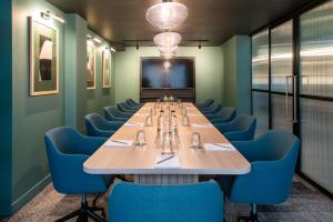 Aparthotel Birmingham في برمنغهام: قاعة اجتماعات مع طاولة طويلة وكراسي زرقاء