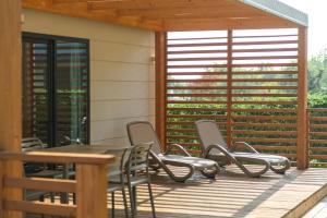 una terraza de madera con sillas, mesa y ventana en Camping Toscolano, en Toscolano Maderno