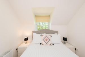 a bedroom with a white bed with a pink pillow at The Pines in Middlesbrough