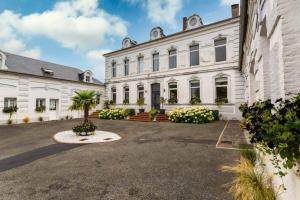 un grand bâtiment blanc avec un palmier dans la cour dans l'établissement Le Clos, à Hucqueliers