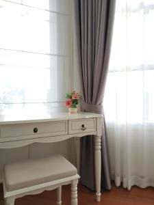 a white desk with flowers on it next to a window at Hamilton House in Ban Sathani Bandai Ma