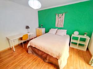 una camera da letto con parete verde, letto e scrivania di Villa Peponi a Ericeira