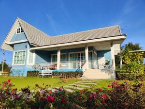 a blue house with a porch and flowers at Hamilton House in Ban Sathani Bandai Ma