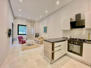 a kitchen with a counter top and a living room at Chez Dadou - joli Apt Marsa Safsaf in La Marsa