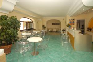 ein Zimmer mit Tischen und Stühlen auf einem Fliesenboden in der Unterkunft Hotel Imperamare in Ischia