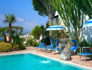 a swimming pool with blue chairs and an umbrella at Hotel Imperamare in Ischia