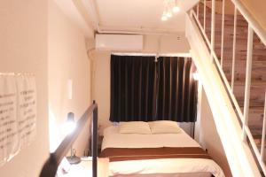 Una pequeña habitación con una cama y una ventana. en Imperial 心斎橋本町, en Osaka