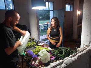 a man and a woman standing next to a table of vegetables at Yanvii_factory in Aldina Seconda