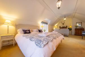 a bedroom with a large bed with white sheets at The Coach House in Flitcham