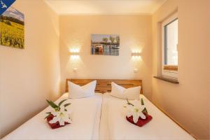 2 Betten in einem Zimmer mit weißer Bettwäsche und Blumen in der Unterkunft Ferienhaus Janina Ferienhaus Janina in Zinnowitz