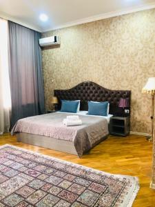 Schlafzimmer mit einem Bett mit blauen Kissen und einem Teppich in der Unterkunft Pilot hotel Baku center in Baku