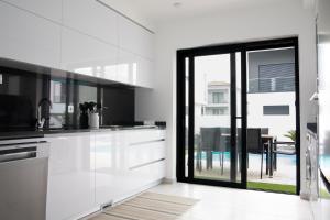 uma cozinha com armários brancos e uma porta de vidro deslizante em Villa Besugo - SCH082 em Pataias