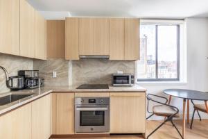 uma cozinha com armários de madeira e uma mesa com um micro-ondas em Chelsea 1br w doorman elevator nr High Line NYC-601 em Nova York