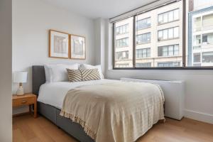 a white bedroom with a bed and two windows at Chelsea 1br w doorman elevator nr High Line NYC-601 in New York