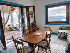 a living room with a wooden table and chairs at Scirocco Eolie with sea view! in Lipari