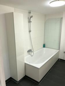eine weiße Badewanne in einem Zimmer mit Dusche in der Unterkunft Außenalster Penthouse Charakter in Hamburg