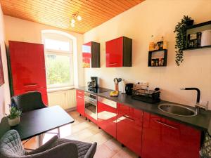 a kitchen with red cabinets and a sink at R2 - Urlaubsmagie - 5 Fussminuten zur Elbe, Pool in Rathmannsdorf