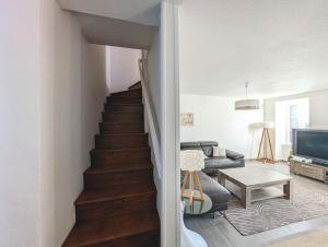 ein Wohnzimmer mit einer Treppe, einem Sofa und einem TV in der Unterkunft Plage & Marais - Maison 3 chambres 6 personnes - in Guérande