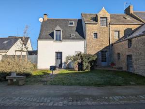 ein großes Backsteinhaus mit einem Hof mit einer Bank in der Unterkunft Plage & Marais - Maison 3 chambres 6 personnes - in Guérande