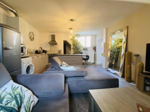 uma sala de estar com dois sofás azuis e uma cozinha em Le Pigeonnier em Rodez